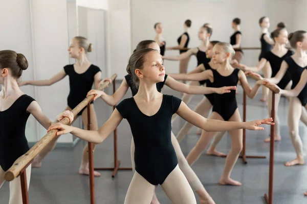 若いバレリーナ バレエ クラスでリハーサルします 彼らはさまざまな振付演習を実行します バレエ バール近くの別の位置に立つ — ストック写真