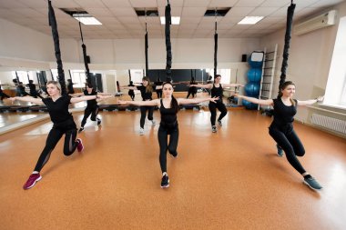 Siyah spor giyim giyen bir grup aktif spor kızı spor salonunda muhabbet kuşu fitness oynuyorlar. Spor salonunda bungee jumping