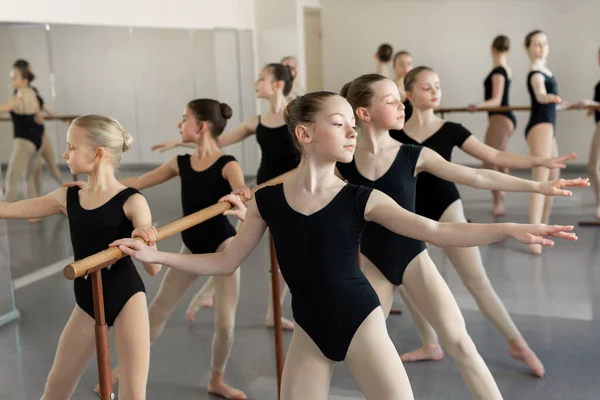 年轻的芭蕾舞在芭蕾舞课上排练 他们进行不同的舞蹈练习 他们站在不同的位置附近的芭蕾巴尔 — 图库照片