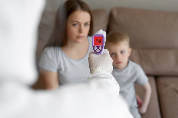 의사는 이마에 적외선 온도계를 사용하여 소녀와 그녀의 아들의 체온을 코로나 — 스톡 사진