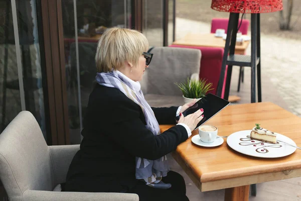 Una Anciana Con Gafas Negras Trabaja Una Tableta Café Calle — Foto de Stock