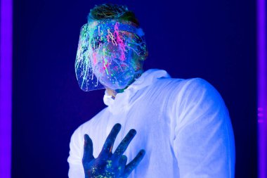 Korunaklı giysiler içinde, koronavirüs salgını sırasında ultraviyole ışıklı insan portresi. Salgın, Coronavirus covid-19 salgını.