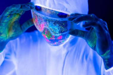 Korunaklı giysiler içinde, koronavirüs salgını sırasında ultraviyole ışıklı insan portresi. Salgın, Coronavirus covid-19 salgını.