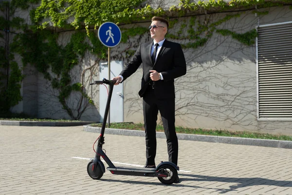 Siyah Takım Elbiseli Bir Adam Elektrikli Scooterın Yanında Duruyor — Stok fotoğraf