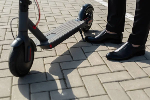 Bir Adamın Ayaklarının Elbisesi Elektrikli Scooter Yanındaki Ayakkabılarının Yakın Çekimi — Stok fotoğraf