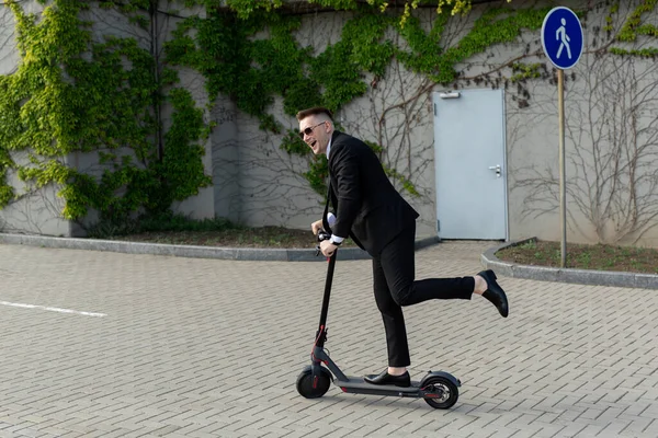 Takım Elbiseli Güneş Gözlüklü Bir Adam Elektrikli Scooter Kullanıyor Gülüyor — Stok fotoğraf