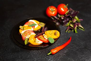 Domatesli Caprese salatası, mozzarella peyniri, fesleğen. Karanlık arka plan. Kapatın. Üst görünüm.