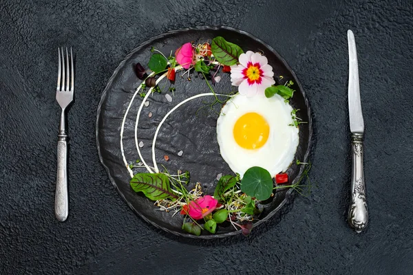 Stock image Fried egg with a decor of microgreens, food flowers, sorrel and nasturtium.