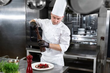 Otel ya da restoran mutfağında aşçı, baharatlı yemekler yapıyor.