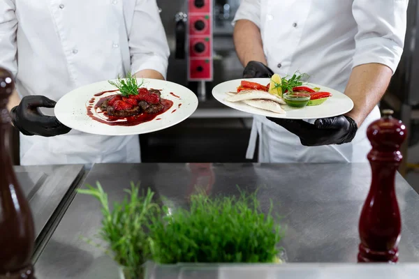 Dos Chefs Una Cocina Profesional Sostienen Platos Listos Sus Manos — Foto de Stock
