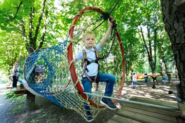 Little boy walking on an obstacle course. A rope tow clipart