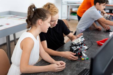 Okul çocukları sınıfta bir robot programlıyor.
