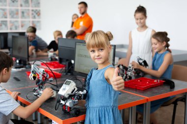 Portre öğrencisi kollarında robot tutuyor. Robot bilimi dersinde bir bilgisayara programlanmış plastik parçalardan bir araya getirilmiş.