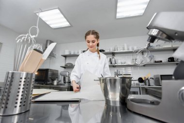 Pasta şefi mutfakta parşömen kesiyor..