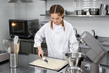 Pasta şefi pişirmeden önce bisküviyi parşömenin üzerine koyuyor..