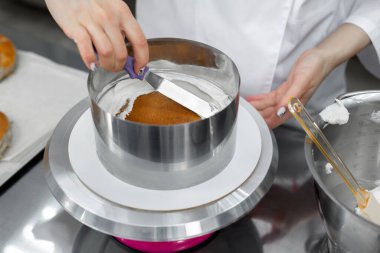 Pasta şefi kremayı spatulayla hizalar..