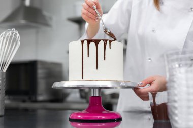 Pasta şefi pastayı çikolata çizgileriyle süslüyor..