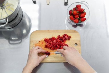 Kadın ellerinin kesme tahtasında çilek kesmesine yakın durun.