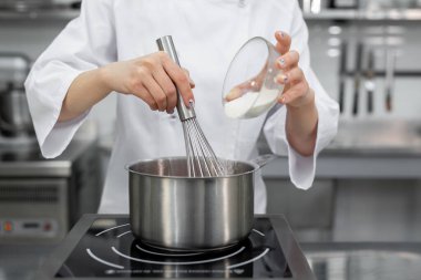 Pasta şefi tencereye çilekli püre ile şeker ekler..