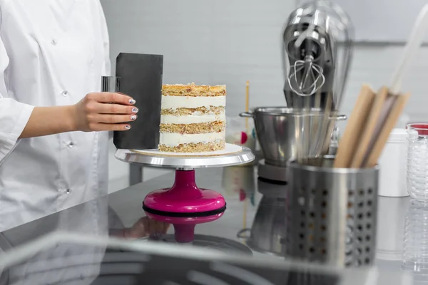 Stock image The pastry chef levels the cake with cream