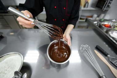 Pasta şefi çikolatalı ganache ile çırpıcıyı karıştırır..