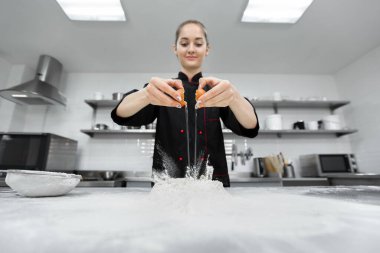 Pasta şefi beyaz un üzerinde yumurta kırıyor.