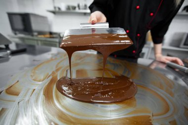 Erimiş çikolatayı yumuşatan spatula kullanan bir pasta şefinin yakın çekimi.