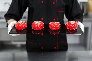 Bir pasta şefinin ellerinde köpüklü keklerin yakın çekimi..