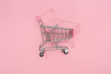 Pembe arka planda boş küçük alışveriş sepeti.