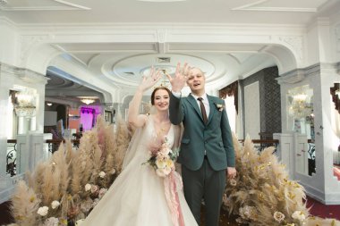 Yeni evliler güzel düğün törenlerinde güler ve yüzüklerini gösterirler..