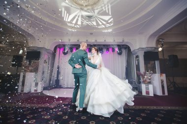 Gelin ve damat düğün töreninde altın konfeti altında dans ediyorlar..