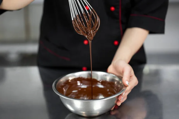 stock image Pastry chef whips melted chocolate in a bowl with a metal wire whisk close up