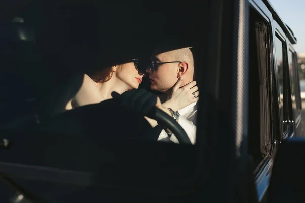 Νύφη Και Γαμπρός Φιλιούνται Ένα Μεγάλο Μαύρο Αυτοκίνητο — Φωτογραφία Αρχείου