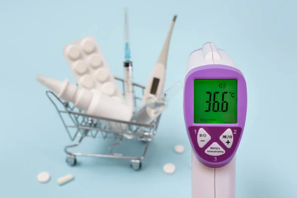 Berührungsloses Thermometer Auf Dem Hintergrund Eines Korbs Mit Medikamenten lizenzfreie Stockfotos