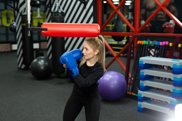 Kadın sporcu boks ringinde simülatörde yumruk pratiği yapıyor.