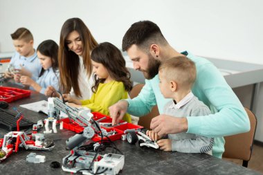 Robot kulübünde çocuklu bir aile bir robotu inşaatçıdan kontrol eder.