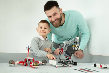 Babam oğluyla robot arabalarında robot dersinde oynuyor.