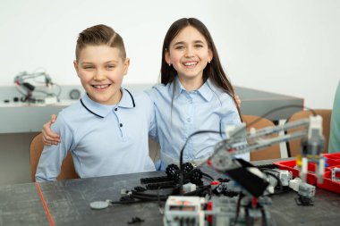 Bir grup çocuk plastik parçalardan yapılmış robotlarla oynuyorlar.