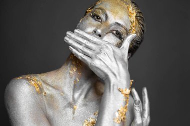 Stüdyoda, cildinde ve saçlarında altın ve gümüş rengi boya olan güzel bir kadın modelin portresi.