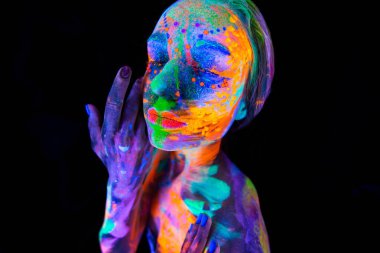 Neon ışıklı güzel bir genç kadın. Renkli makyajlı ve ultraviyole ışıkta poz veren floresan makyajlı bir modelin portresi