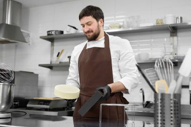 Erkek pasta şefi silikon bir kalıptan donmuş kremalı pasta çıkarıyor..