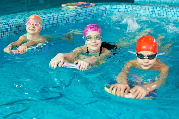 男の子と女の子のグループは インストラクターと一緒にプールで泳ぐことを学びます 子供スポーツの発展 — ストック写真