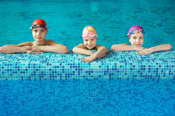 練習中にプールの端のカメラを見て微笑む楽しい子供たちのグループ — ストック写真