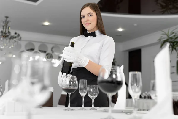 戴白手套的女服务员把红酒倒进杯子里 — 图库照片
