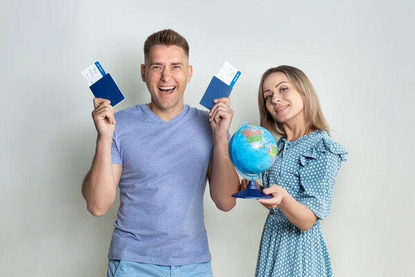 Cheerful young tourists in sunglasses, a guy and a girl isolated on a white background with a globe, passports and tickets in their hands.