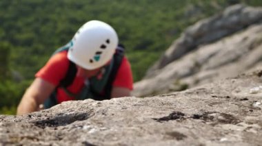 Genç erkek tırmanışçı zor bir yolda bir dağa tırmanır.