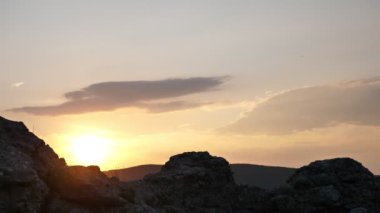 Gün batımında dağın tepesinde elinde teçhizat ve iple tırmanıyor.