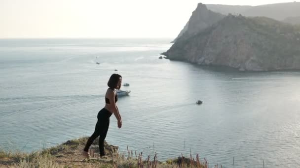 日没時に海を見下ろす崖の端にある複雑なヨガのポーズで瞑想 なたらじゃじゃさな — ストック動画
