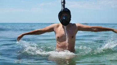 Genç bir adam maskesiyle denize dalıyor.