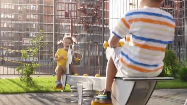 子供たち 男の子と女の子は 新鮮な空気の中でスイングを楽しんでいます 公園での楽しみ — ストック動画